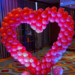 A large, vibrant red heart-shaped balloon arch. This internally lit structure is perfect as a bold statement piece for an anniversary party or Valentine's event.