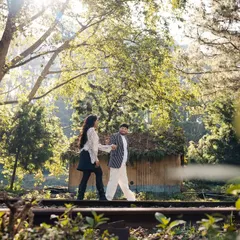 A candid moment of a couple walking along old railway tracks, surrounded by lush greenery. These pre-wedding shoots are perfect for capturing your adventurous side.