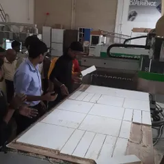 Students work together to arrange freshly cut components from a large panel processed on the CNC machine, a common workflow in modern modular furniture production.