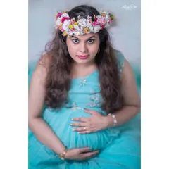 A close-up studio shot that focuses on the mother's direct gaze. The floral crown and elegant gown create a look that is both classic and beautiful.