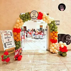 The entrance to the 'Cars' party, featuring a balloon arch in theme colors, a personalized welcome sign, and fun props like a stack of tires.