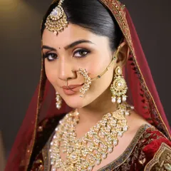 A close-up of a regal bridal look. The focus is on the flawless makeup, featuring bold eyes with a traditional nath and a rich velvet lehenga, perfect for a winter wedding.
