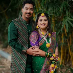 A lovely couple portrait from their Haldi day. They are dressed in matching green outfits, standing together against a natural bamboo backdrop, smiling happily for the camera.