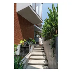 A key design strategy is to create pathways that connect the inhabitants with nature. Here, a set of exterior concrete steps runs alongside a water channel and lush planting, leading up from the garden and blurring the line between the built form and the landscape.