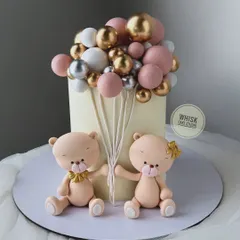 A cute and simple baby shower cake. This design features two adorable teddy bears holding a bouquet of pink, gold, and white balloons.
