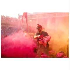 A man prepares to throw a bag of colored powder into the crowd. This is a moment of anticipation just before the explosion of color, showing the energy of the festival.