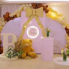 The main backdrop for the "Baby Singh" shower. A large teddy bear sits next to a personalized light-up sign, all framed by a stunning balloon arch in shades of brown, yellow, and cream.