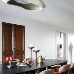 This dining room strikes a perfect balance between rich textures and bold forms. Warm chocolate brown chairs bring coziness, while the sleek black marble table adds modern sophistication. The contemporary pendant lamp ties it all together.