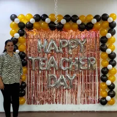 A happy client posing in front of our Teacher's Day backdrop. This demonstrates how our decorations serve as a great photo opportunity, helping create lasting memories of office celebrations.