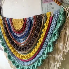 A close-up of our semi-circular rainbow tapestry, showing the rich textures created by combining different macramé and crochet techniques and colors.