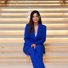 A full-length shot in a vibrant blue suit, a key piece in my corporate wardrobe. Power dressing is a conscious choice to project confidence and command attention from the moment I step into the venue.