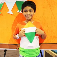 A young boy proudly holds up his tricolor kite craft. My Independence Day workshop includes patriotic art activities that let kids celebrate the occasion in a creative and personal way.