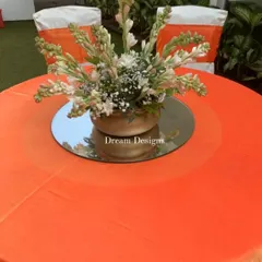 The table decor for a Mehndi party, featuring a bright orange tablecloth. The simple floral centerpiece with tuberoses provides a fresh and fragrant touch.