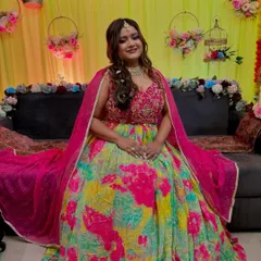 A beautiful Mehendi bride, ready for her ceremony. The makeup is bright and glowing, with a pop of pink on the lips to match her colorful outfit.