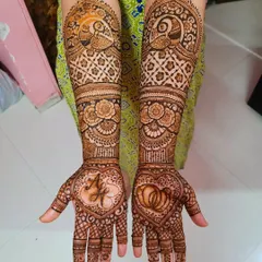 A beautiful engagement henna set featuring the couple's initials and wedding rings inside hearts on the palms, surrounded by traditional peacock and floral work.