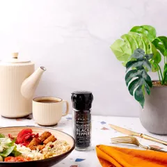 A lifestyle shot featuring Sprig's Tellicherry Black Pepper on a modern breakfast table. The clean, minimalist aesthetic positions the product as a premium addition to a healthy and stylish meal.