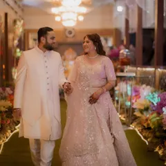 A beautiful shot of the engaged couple walking hand-in-hand down a flower-lined path, sharing a look of love and happiness.