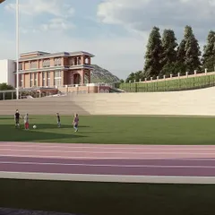 A view from an arched gateway shows the expansive sports field and running track at the heart of the school campus. We believe that world-class athletic facilities are essential to a modern educational institution, and we integrate them fully into our master plans.