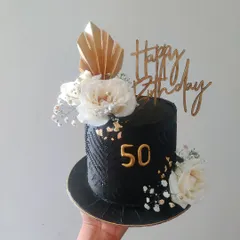 Celebrating a 50th birthday calls for something truly special. This striking black cake features a sophisticated textured pattern, elegant white florals, and gold accents, creating a modern and memorable centerpiece for a milestone celebration.