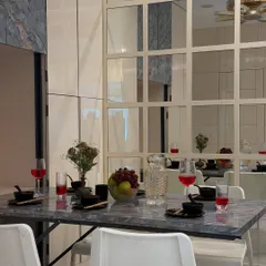 A detailed shot of the dining setup, showing the elegant marble-patterned tabletop against the gridded mirror wall. These details create a feeling of luxury and openness.