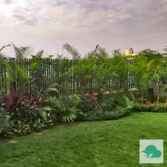 This garden features a dense border of tropical plants, including various palms and flowering shrubs, set against a bamboo fence. This technique provides excellent privacy and creates the feeling of a secluded tropical paradise.