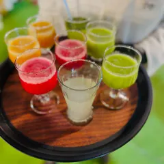 A tray of colorful fresh juices, including watermelon, orange, and green juice. These vibrant and healthy drinks are a perfect welcome beverage for any event.