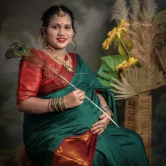 A moment of quiet joy. This mother-to-be, dressed in a lovely green and red saree, holds a peacock feather, a symbol of grace, during her studio maternity session.