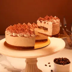 We present a taste of Italy with our classic Tiramisu cake. Featuring layers of coffee-soaked ladyfingers and creamy mascarpone, this cake is finished with piped cream and a generous dusting of cocoa powder for an authentic and elegant dessert experience.