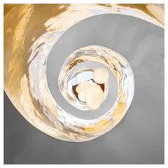 A view from the top of the Cleft House shows the spiraling light fixture, which mimics the form of the staircase below. This detail emphasizes the vertical axis of the home and adds a touch of artistic elegance to the rugged architectural shell.
