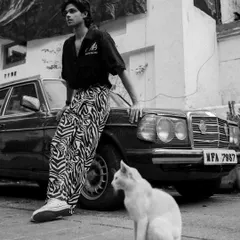 An unposed moment during an urban fashion shoot, where a cat wandered into the frame. This adds a touch of spontaneity and story to the editorial shot.
