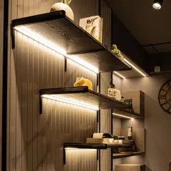 We use lighting to accentuate architectural details. Here, LED strips are concealed beneath each shelf, highlighting the texture of the grooved back panel and casting a soft, ambient light on the decorative items.