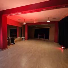 Another angle of the studio under a warm red light. You can see the clean, open layout and the professional blackout curtains that give you a blank canvas for any lighting setup.