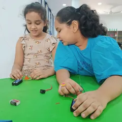 Two students working together to understand the basics of electricity. They are connecting batteries and wires to create a simple circuit, a fundamental skill for any young inventor.
