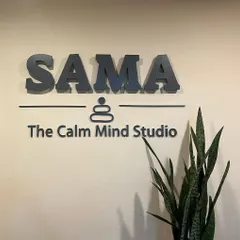 The SAMA logo on our studio wall, next to a snake plant that helps purify the air. Every detail here is chosen to contribute to a serene and welcoming atmosphere.