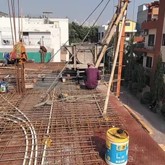 Workers engaged in the slab casting process, with electrical conduits being laid within the rebar mesh before the concrete is poured. This demonstrates the careful coordination required on-site to integrate structural and service-related elements seamlessly.