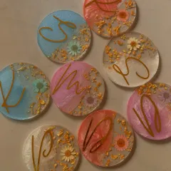 A collection of our custom resin coasters, each with a unique initial and color blend. We can create these in various pastel and pearlescent shades to match your event's theme.