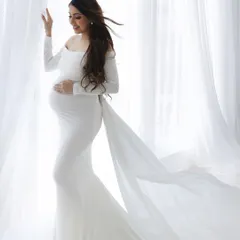 Angelic and serene. This mom-to-be looks absolutely radiant in a classic white gown with a flowing train, creating a timeless and ethereal portrait.