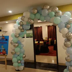 A stylish balloon arch in pastel blue, green, and silver, welcoming guests to a 4th birthday party.