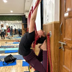 This student demonstrates great focus while using the ropes and wheel to deepen his backbend. This setup is excellent for building confidence and exploring the full potential of the spine.