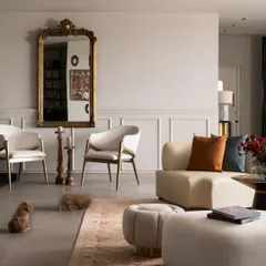 A comfortable seating arrangement in our experience center, where classic elements meet contemporary design. A vintage-style gilt mirror is paired with modern curved sofas and armchairs, demonstrating how I mix styles to create timeless and welcoming spaces.