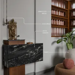 This pooja corner is a perfect example of material harmony. A floating black granite slab is supported by a wooden base, while a traditional brass lamp and idol add a touch of gold.