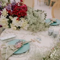 This place setting from a spring luncheon features a custom floral-print tablecloth, a sage green scalloped napkin, and a beautiful laser-cut wooden flower as a napkin ring.