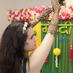 A fun, candid shot of the bride dancing and celebrating during her Mehndi ceremony, showing off her beautiful henna-adorned arms.