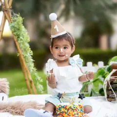 A close-up of the birthday girl enjoying her cake. The blurred green background of the park keeps the focus right on her happy face.
