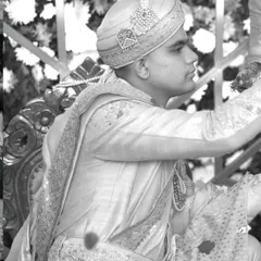 A classic black and white portrait of the groom during the wedding ceremony, his expression focused and serene.