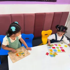Two girls work on shape and animal puzzles together. Collaborative play is encouraged to help children develop social skills like sharing and communication while they learn.