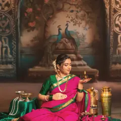 A moment of tranquility and light. The mother-to-be holds a traditional diya, its warm glow illuminating her face. This shot, set against a painted backdrop of peacocks, is rich with cultural and artistic meaning.