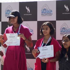 Proud winners on the podium after the swimming competition, showcasing their certificates and medals.