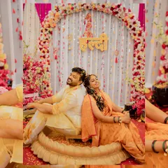 A lovely portrait of the couple sitting back-to-back during their Haldi ceremony, surrounded by a beautiful floral decor.