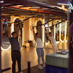 A trio in sync during a TRX overhead squat, a great exercise for building shoulder stability and leg strength. Group classes help you stay motivated and push your limits together.